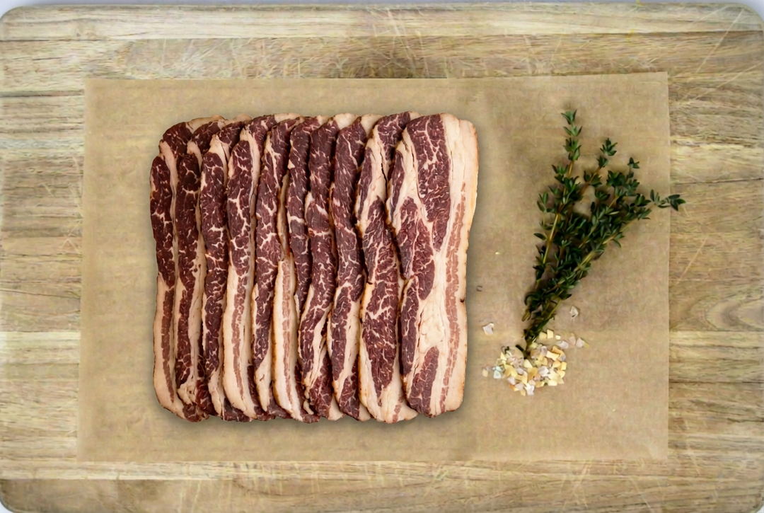Uncooked beef bacon slices on parchment over a pale wooden cutting board.